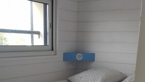 A small, single-bed room with a window, a blue headboard, and a white wall.