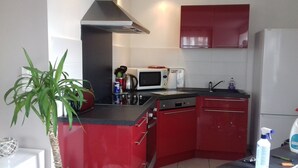 A compact kitchen with red cabinets, a microwave, a stove, and a sink.