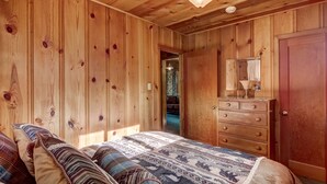 A wooden-paneled bedroom with a bed, dresser, and a mirror. - 3993c Cedar Lake Tahoe 2 Bedroom Cabin by RedAwning (South Lake Tahoe)