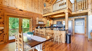 L’intérieur d’un chalet en bois comprend un coin repas, une cuisine et un balcon.