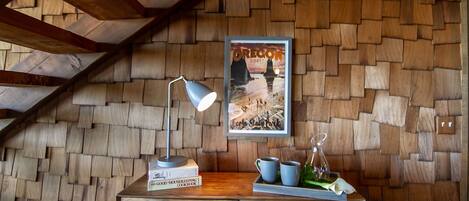 A wooden desk with a lamp, a framed poster, and a tray with cups and a pitcher.