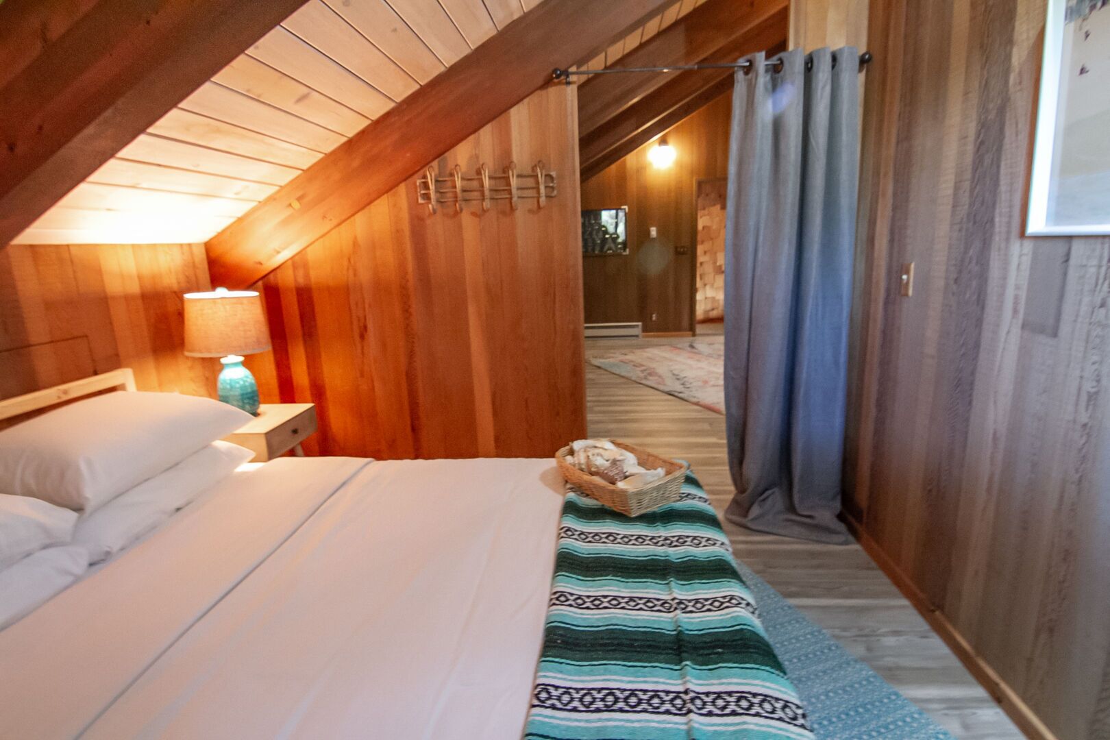 Une chambre confortable avec un lit, une table de chevet, une lampe et un panier de pain posé sur le sol.