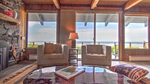 A cozy room with two armchairs, a glass coffee table, and a view of the ocean. - Ocean Front on Miles of Sandy Beach! Dog Friendly! (Yachats)