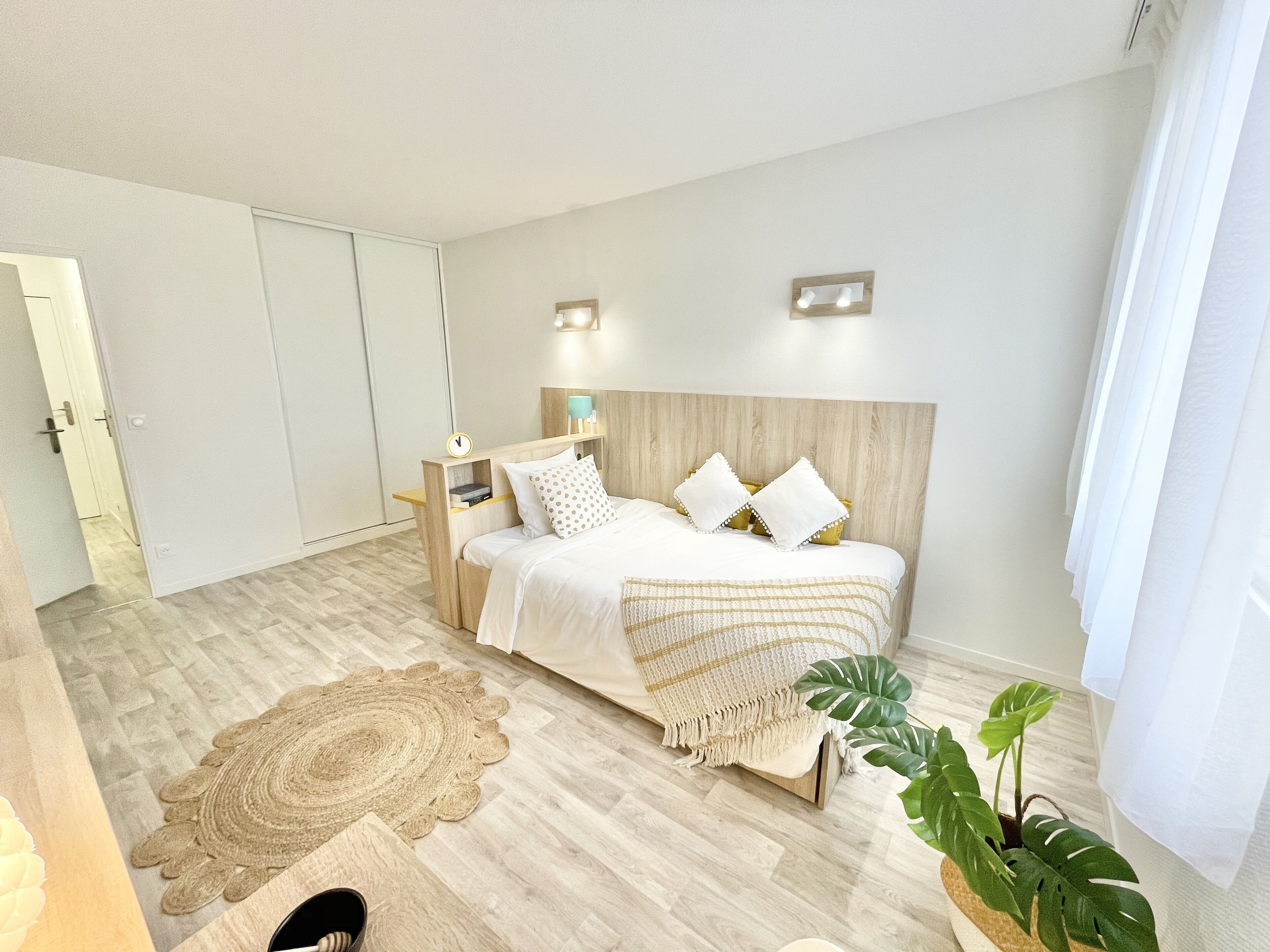 Une chambre à coucher moderne avec un lit, une table de chevet et une grande plante.