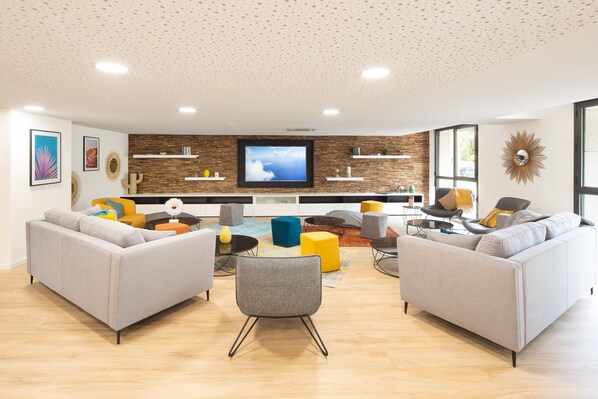 A modern living room with two sofas, a coffee table, and a TV. - Residence Sweetly St Augustin (Bordeaux)