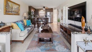 A living room with a sofa, coffee table, TV, and kitchen area.