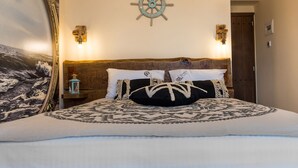 Ein Bett mit Kopfteil im Seestil, eine an der Wand befestigte Schiffslenkrad und zwei Wandleuchten.