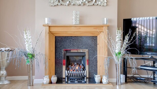 Una sala de estar con chimenea, jarrones decorativos y un televisor.