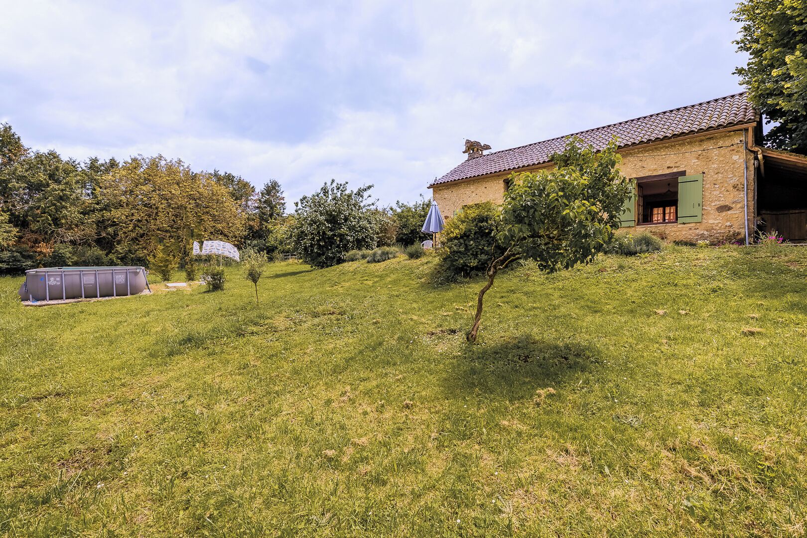 A stone house with a tiled roof, a small garden, and a solar water heater.
