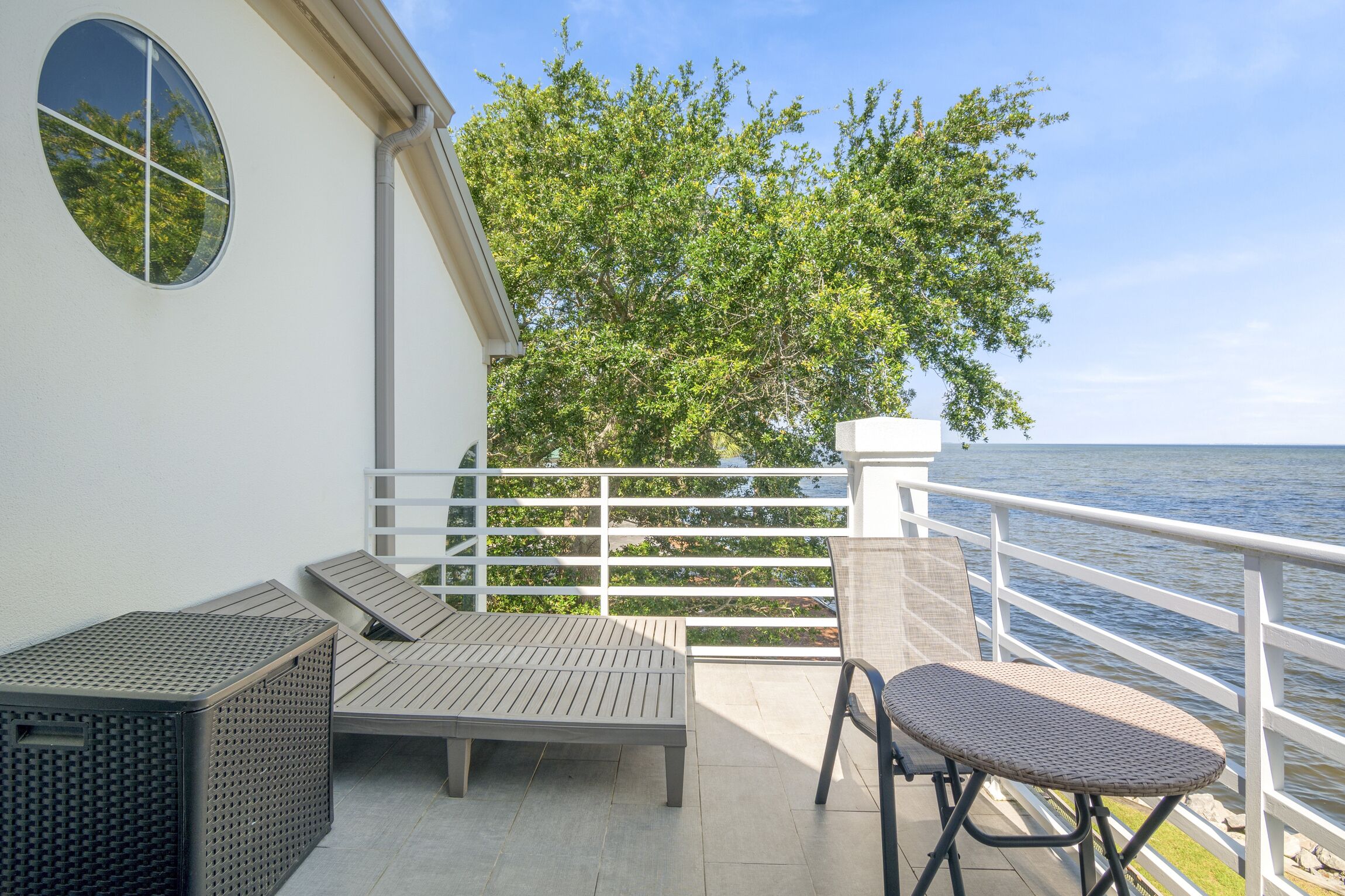 A balcony with a white railing, a small table, and a chair.