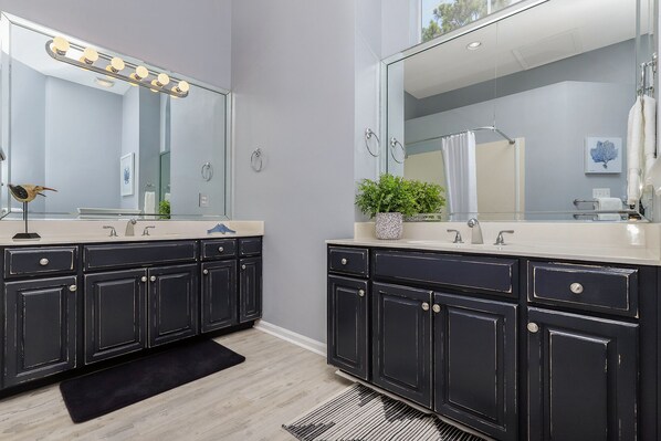 Un baño moderno con dos lavamanos, muebles oscuros y un espejo grande con iluminación.