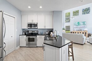 Una cocina moderna con armarios blancos, electrodomésticos de acero inoxidable y una isla con encimera negra.