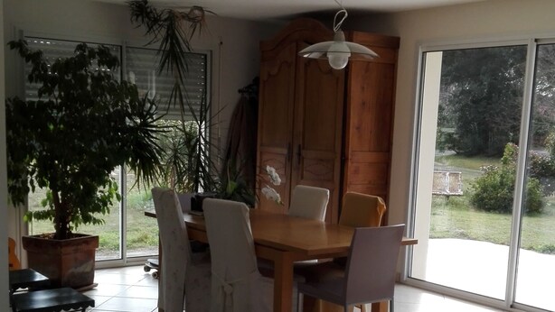 A dining area with a wooden table and chairs, a potted plant, and a view through large windows. - House with two terraces (south and north) and direct access to the bike path. (Messanges)