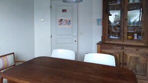 A dining area with a wooden table and chairs, a hanging pendant light, a cabinet with glass doors, and a door with a 'Cuisine' sign. - House with two terraces (south and north) and direct access to the bike path. (Messanges)