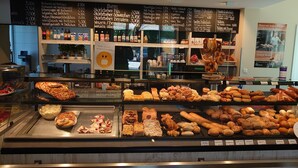 Un expositor de pastelería con diversas opciones horneadas y un panel de menú en la parte superior.