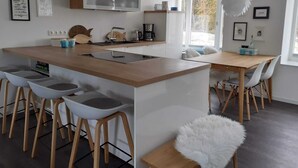 Una cocina moderna con una isla central, taburetes de bar y una mesa de comedor con sillas.
