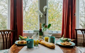 A breakfast table with croissants, a bottle of champagne, and a vase of white flowers. - The Suite, 82 Cathedral, Private Parking (Cardiff)