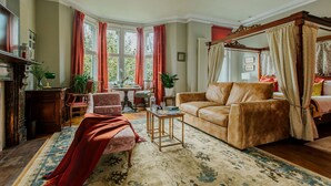A traditional room with a four-poster bed, a leather sofa, and a large window with curtains. - The Suite, 82 Cathedral, Private Parking (Cardiff)