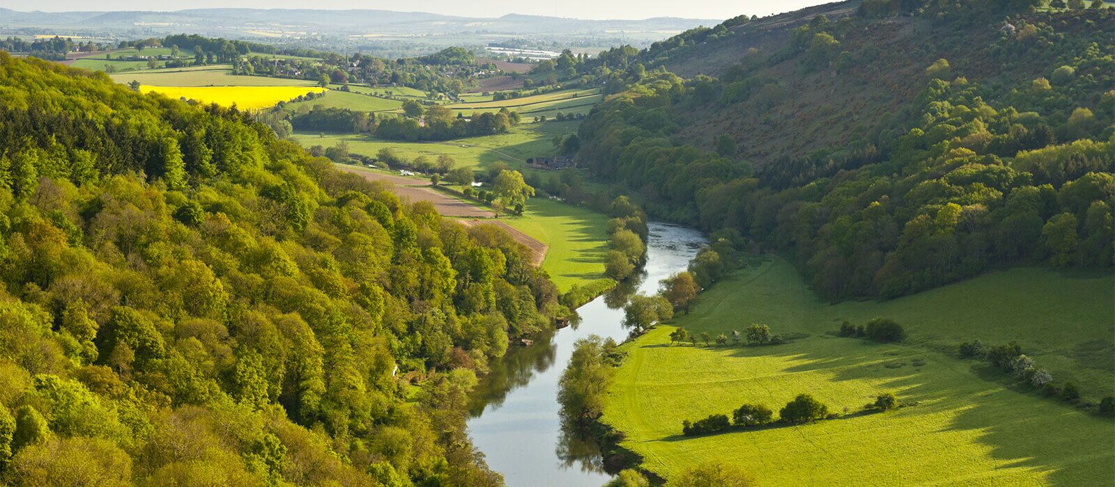 A river winding through a valley with lush greenery and rolling hills.