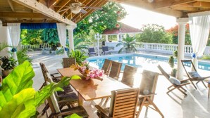 A covered outdoor area with a pool, wooden furniture, and potted plants. - Ace Holiday Room w. Private Bath in Colonial Villa (Sosúa)