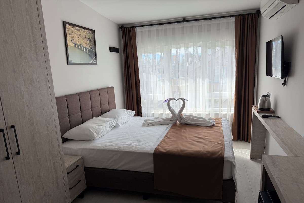 Ein Hotelzimmer mit einem Bett, einem Flachbildfernseher, einer Kaffeemaschine und einem Fenster mit Vorhängen.