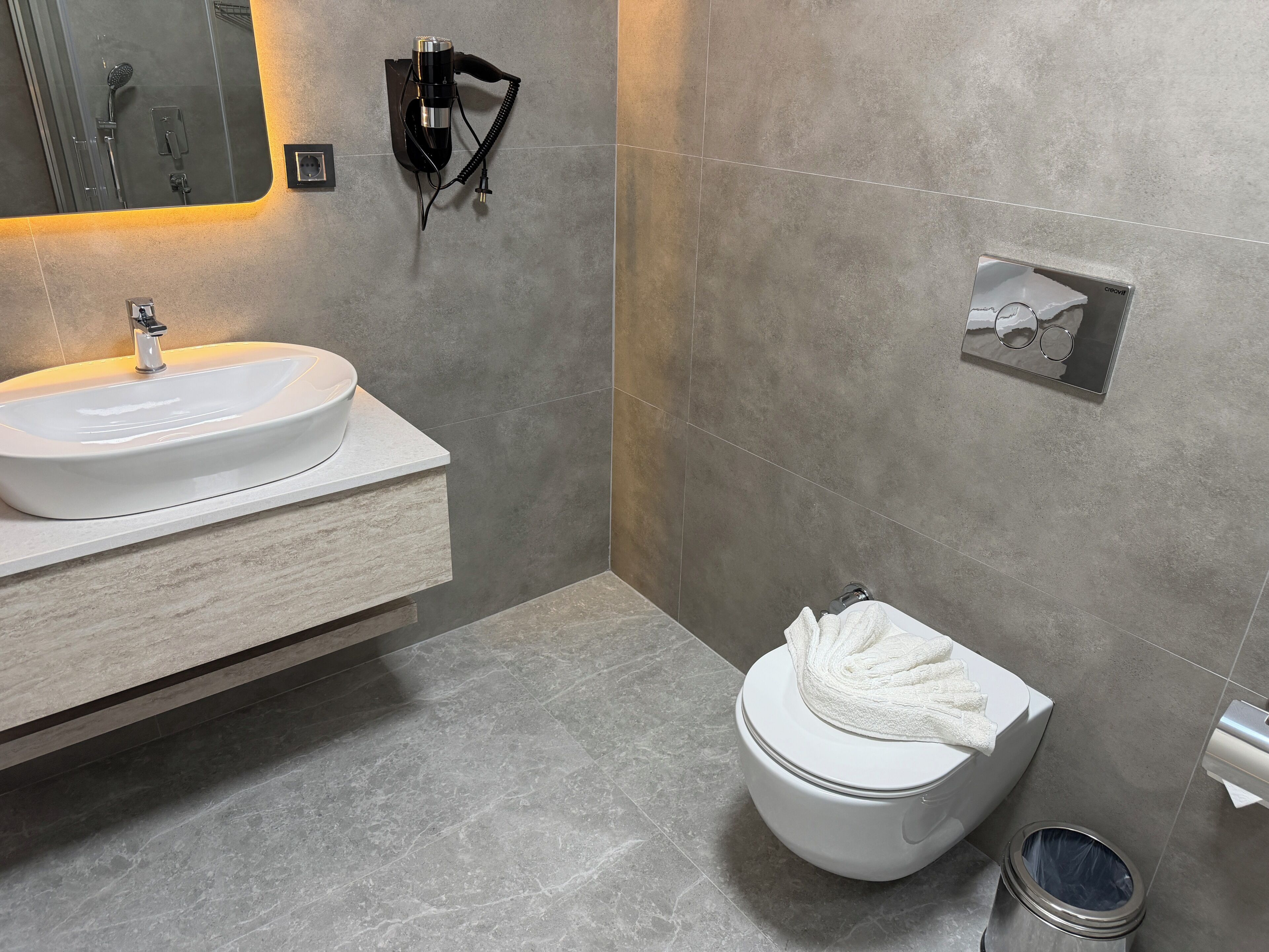 A modern bathroom with a white sink, a toilet, and a shower area.
