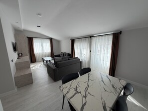 A modern living room with a dining area, a sofa set, and a kitchen area. - ALTINAY HOTEL (Konyaalti)