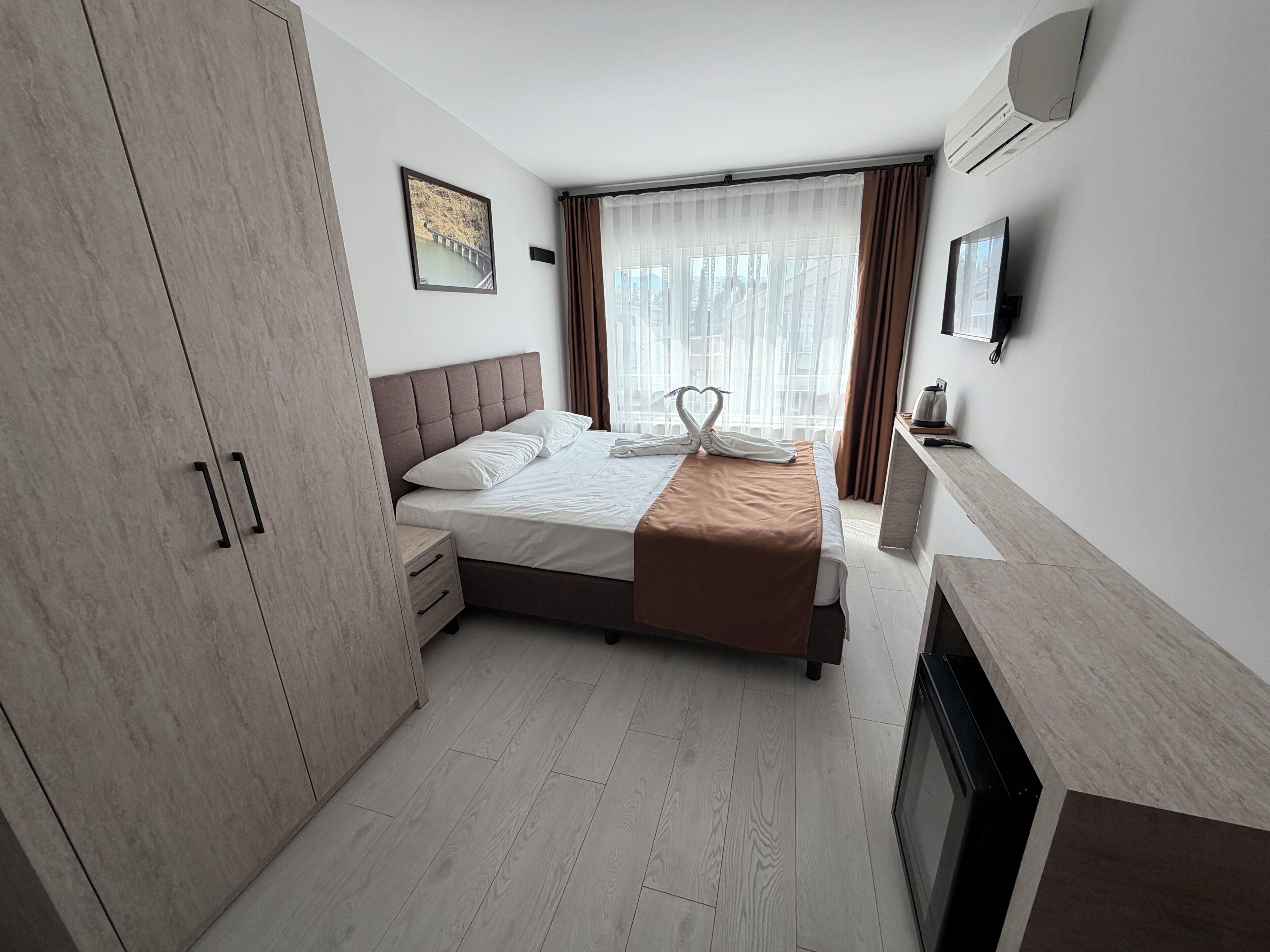A hotel room with a bed, a wardrobe, a bedside table, a fireplace, and a television.