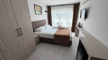 A hotel room with a bed, a wardrobe, a bedside table, a fireplace, and a television.