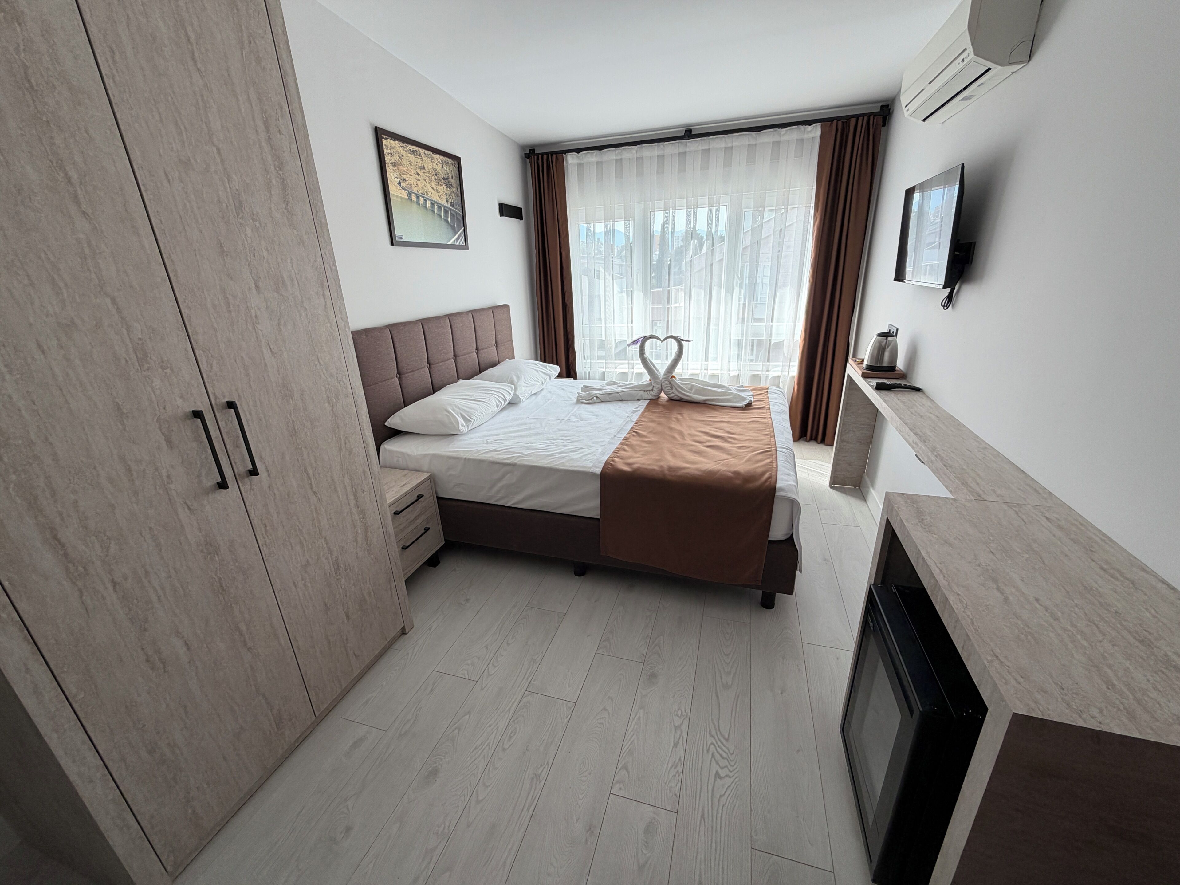 A hotel room with a bed, a wardrobe, a television, and a fireplace.