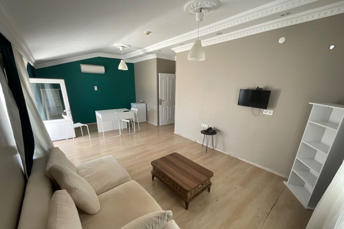 Una sala de estar con un sofá, una mesa de centro y un televisor montado en la pared.