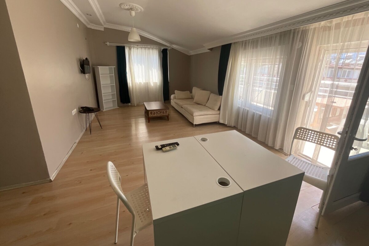 Uma sala de estar moderna com sofá, mesa de centro, televisão e área de refeições.
