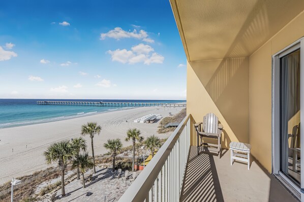 A balcony with a view of a beach and a pier.