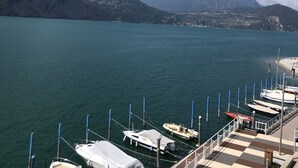 A marina with boats docked, a wooden deck, and a view of mountains and a distant town. - Residenza Liberty on the Lakefront Loft (Marone)