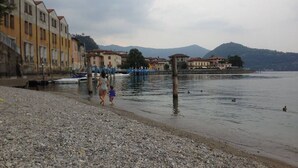 A pebbled waterfront with buildings along the shore and mountains in the background. - Residenza Liberty on the Lakefront Loft (Marone)