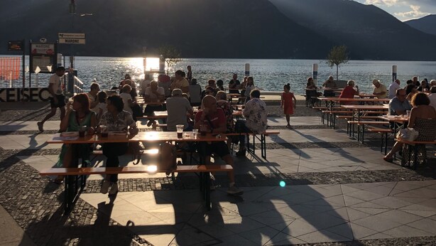 A lakeside terrace with tables and chairs, overlooking a body of water and mountains. - Residenza Liberty on the Lakefront Loft (Marone)