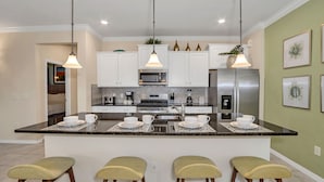 A modern kitchen with white cabinets, a central island with bar stools, stainless steel appliances, and pendant lighting. - Private Pool Home w/Incredible Game Room! FREE Resort Access (Davenport)