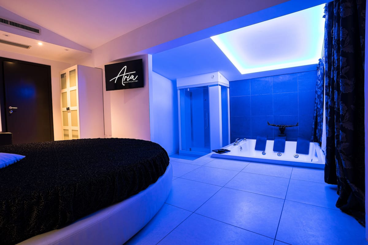 Een moderne slaapkamer met een bed, een wandtelevisie en een badkamer met bad en douche.