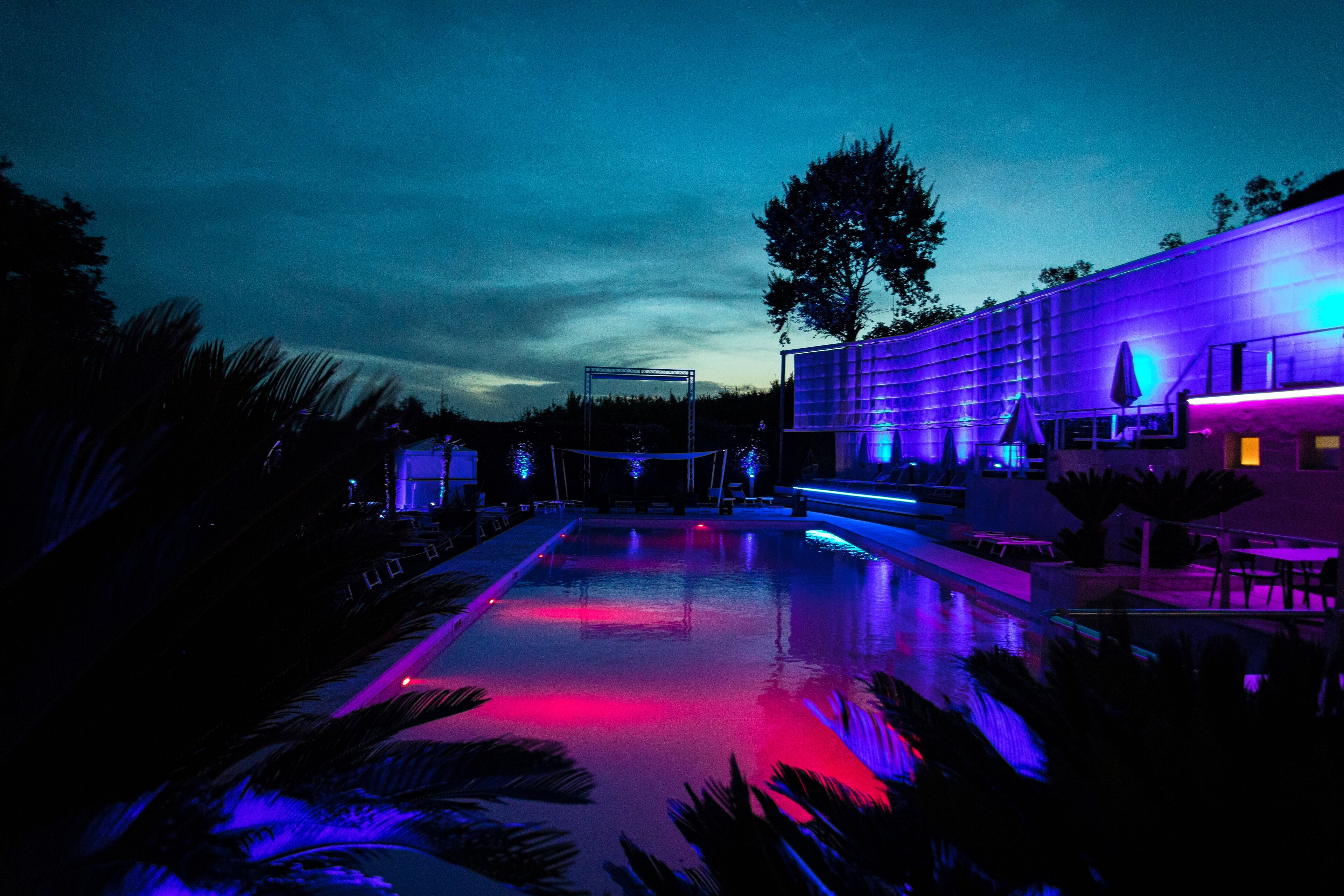 Una piscina con un edificio moderno sullo sfondo, circondata da palme.