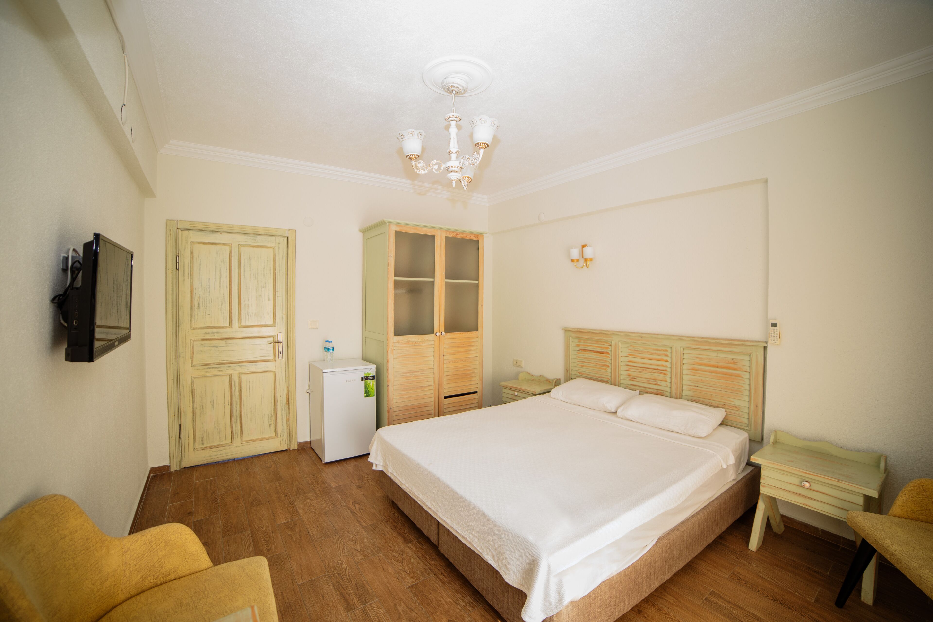 Un dormitorio con una cama grande, un armario de madera y un escritorio pequeño.