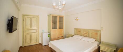 Un dormitorio con una cama grande, un armario de madera y un escritorio pequeño.