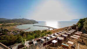 Une zone côtière offrant une vue sur la mer, avec un quai et une rangée de tables et de chaises installées sur la plage.