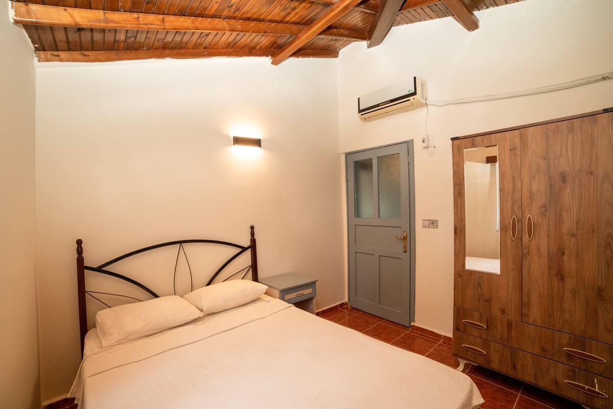 A bedroom with a bed, a nightstand, a wardrobe, and a ceiling fan.