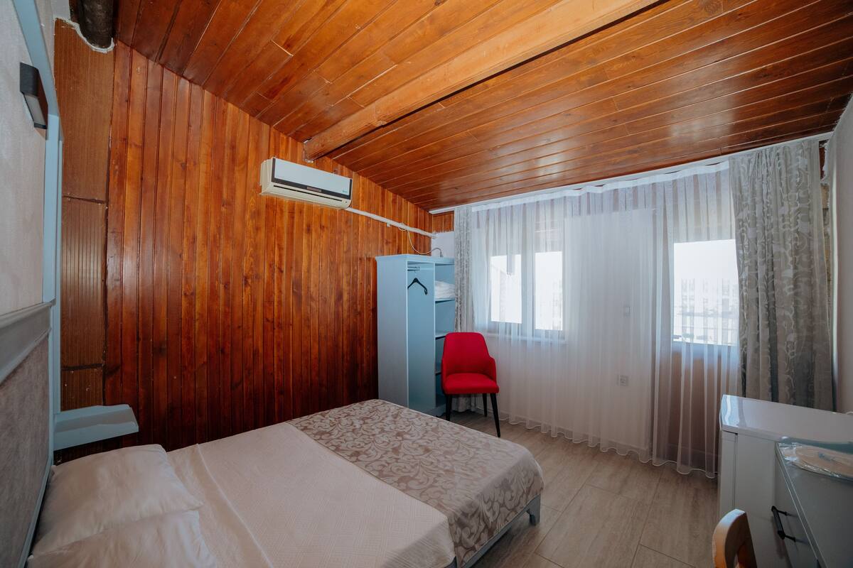 A room with wooden walls, a bed, a desk, and a chair.