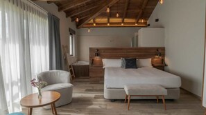 Un dormitorio con una cama grande, una mesita de noche, una silla y una pequeña mesa redonda con flores.