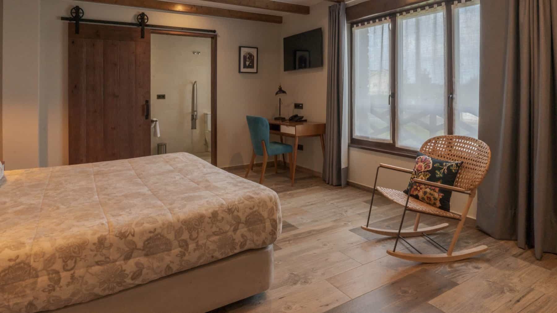 Un dormitorio con cama, escritorio, silla y mecedora.