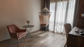 Een moderne kamer met een hangstoel, een ronde tafel met een vaas en een houten bureau.