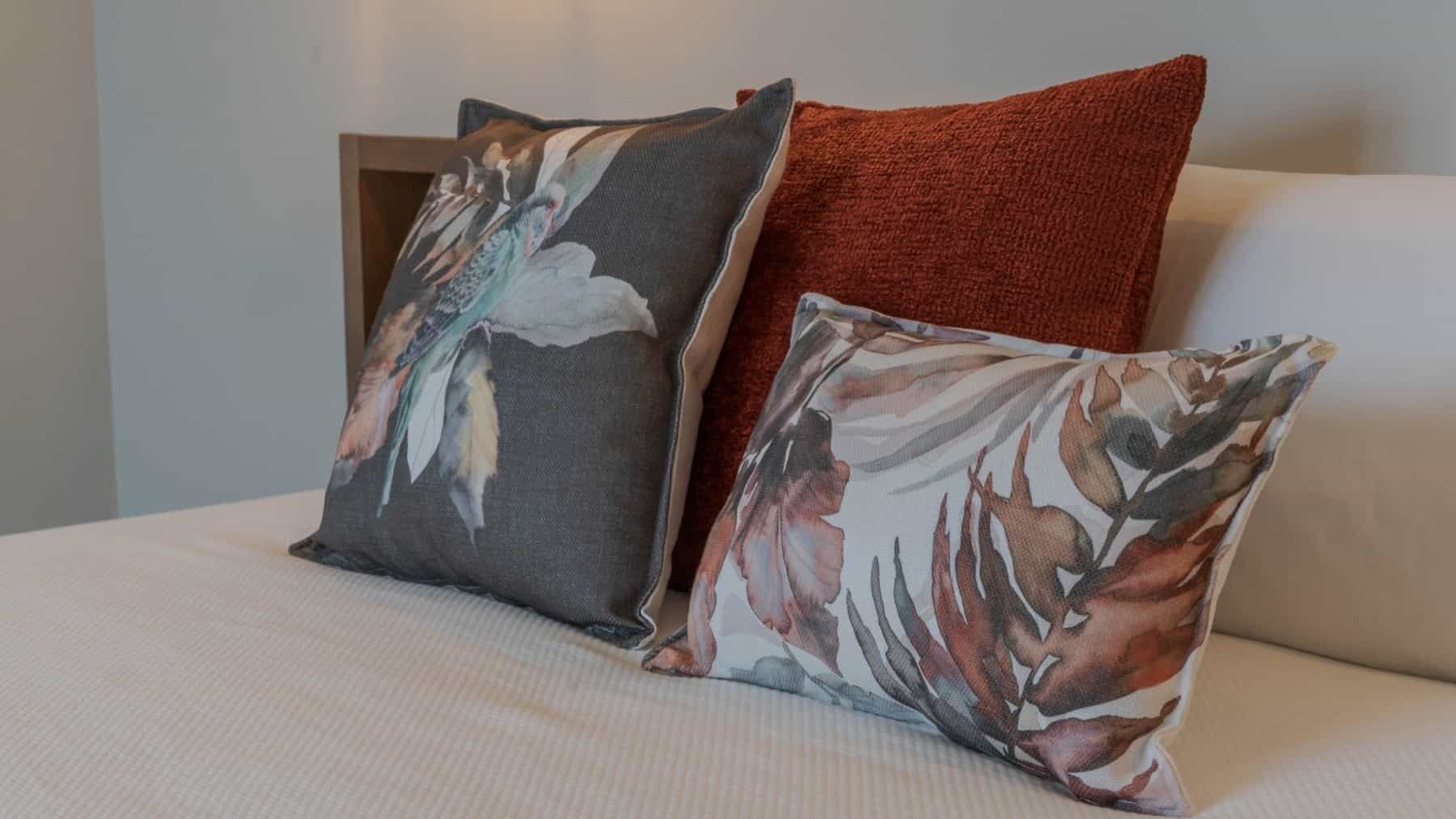 Two pillows with floral designs on a bed.