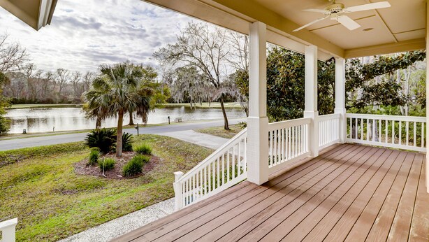 A covered porch with a view of a lake and trees.