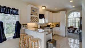 A modern kitchen with white cabinets, a granite countertop, and a built-in island with stools.